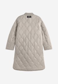 Abrigo acolchado beige con un ajuste relajado, cuello redondo y cierre a presión. La textura es suave con un patrón de ondas en la superficie.