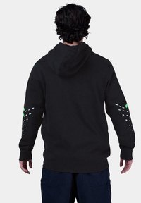 Sudadera negra con capucha, que presenta acentos blancos y verdes en las mangas. Tejido suave con un corte holgado. Vista trasera. Diseño básico sin patrones.