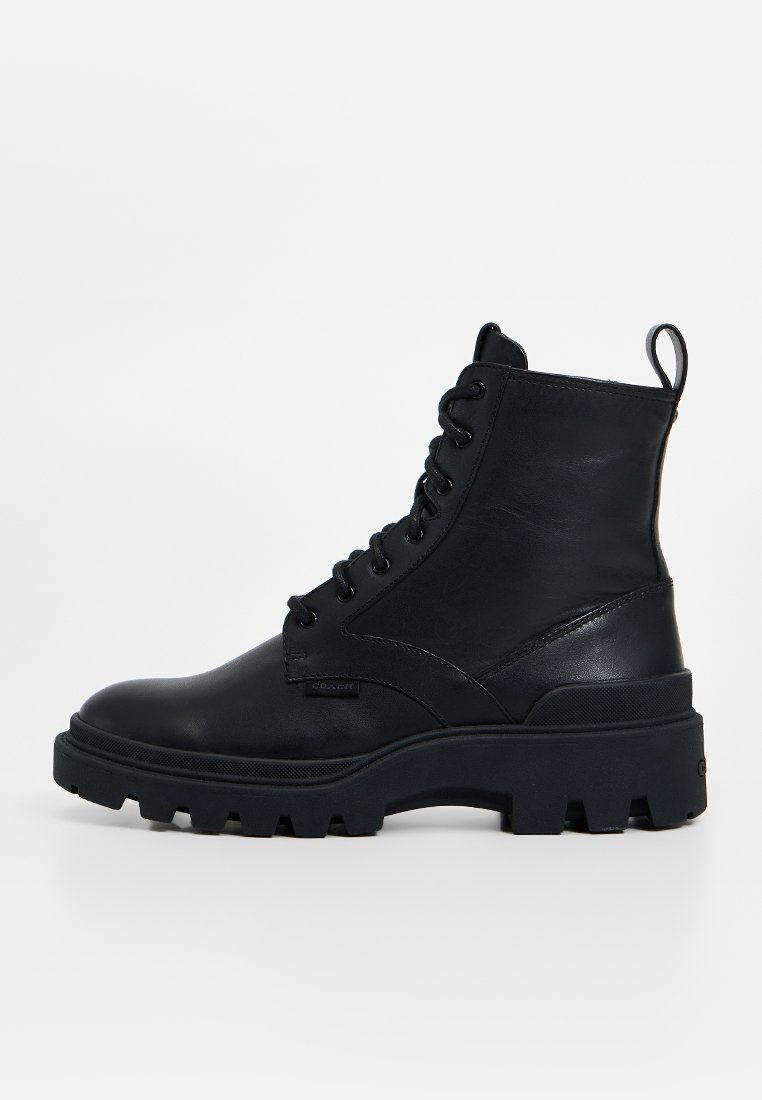 Botte cheville en cuir noir avec un bout rond, à lacets à l'avant, semelle épaisse noire et languette au talon pour un enfilage facile.