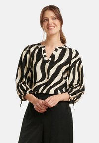 Black and cream zebra-striped blouse with a V-neckline, three-quarter puff sleeves, and ties at the cuffs. Soft, lightweight fabric.