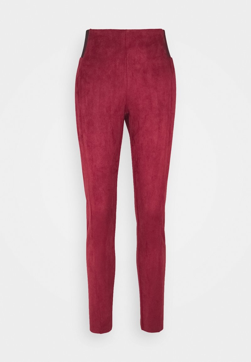 Pantalons en faux suède rouge avec une coupe slim, présentant une texture lisse, une taille haute et des panneaux noirs accentués aux hanches.