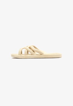 Chanclas beige con correas trenzadas y suelas texturizadas. El diseño presenta tres correas entrelazadas que ofrecen estabilidad y comodidad.