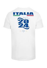 Valge puuvillane t-särk, millel on sinine tekst "ITALIA 2024" ja graafiline keeris. Kaunistatud Itaalia lipu värvide ja dekoratiivsete tähtedega.