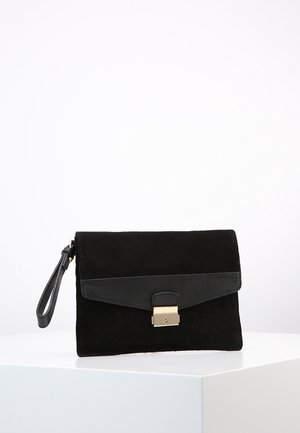 Schwarze Wildleder-Clutch mit Handgelenkriemen und schwarzer Lederklappe, gesichert durch eine kleine goldfarbene Metallschließe, auf einer weißen Fläche präsentiert.