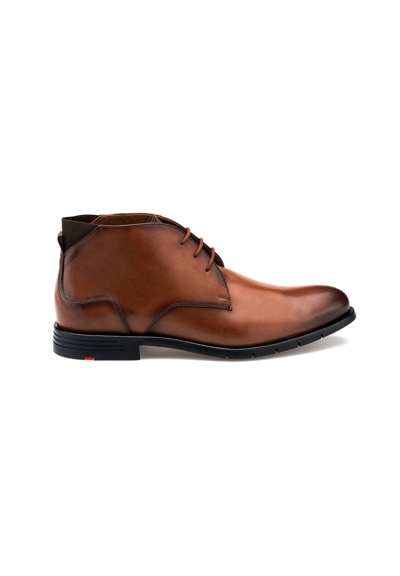 Stivale chukka in pelle marrone con texture liscia, punta rotonda, design con lacci e suola in gomma nera con accentuazione rossa sul tallone.