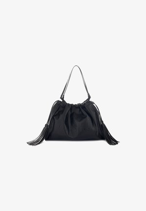 Borsa a tracolla in pelle nera con una sola tracolla, parte superiore arricciata, puntini in rilievo e iniziali, con lunghi pom pom su ciascun lato, su uno sfondo bianco.