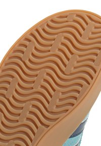 Gummisohle eines Schuhs mit wellenförmigem Profilmuster; die Farbe ist Hellorange mit strukturierten Akzenten. Verfügt über eine glatte Kante und sechseckige Details.