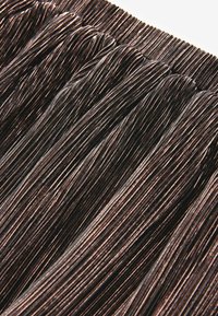 Tessuto cordonato nero e marrone con un design arricciato, caratterizzato da fili fini e strettamente disposti e una superficie testurizzata.