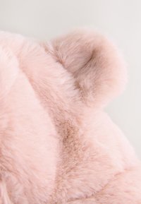 Rožinė dirbtinio kailio medžiaga su minkšta, puria tekstūra. Yra apvalios ausų formos; lygi paviršiaus tekstūra su švelniu blizgesiu ir subtiliu spalvų skirtumu.