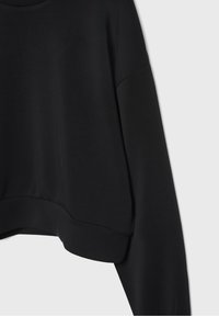 Sudadera negra recortada con mangas largas, textura suave, escote ancho y un ajuste relajado, con un dobladillo acanalado para un detalle adicional.