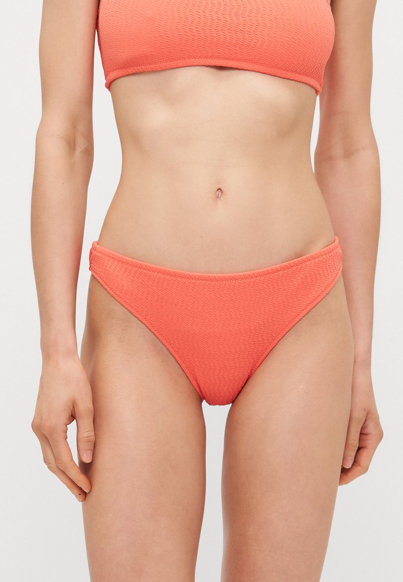 Costum de baie texturat în culoarea corail, compus dintr-un top bandeau și slipuri cu talie joasă. Finish neted cu detalii de cusătură subtile.