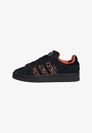 Crne suede tenisice s narančastim unutrašnjosti, s leopard print trakama i crnim vezicama. Ravni crni potplat, klasični nizak dizajn.