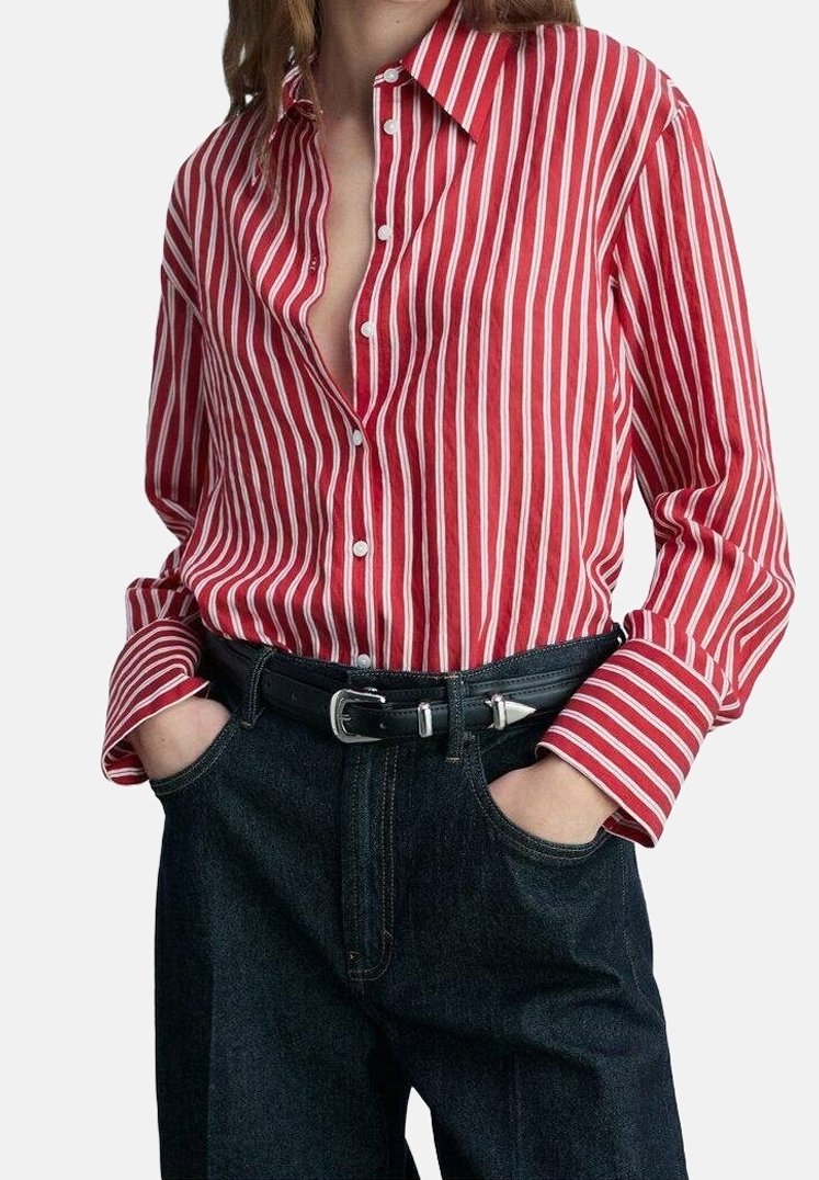 Chemise boutonnée à rayures rouges et blanches avec un col, associée à un pantalon taille haute en denim foncé et une ceinture noire.
