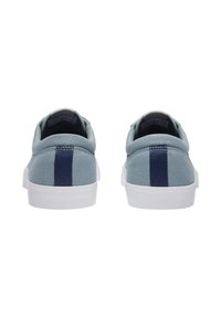 Baskets en toile bleu clair avec semelles en caoutchouc blanches, comportant une rayure verticale navy à l'arrière et un col rembourré doux.