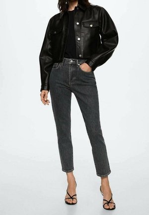 Black leather cropped jacket with two front pockets, paired with high-waisted dark gray jeans and black strappy sandals.