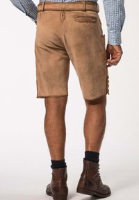 Pantalones cortos de ante marrón con bolsillos laterales, cortados por encima de la rodilla, combinados con botas de encaje marrón oscuro y calcetines marinos, vistos desde atrás.
