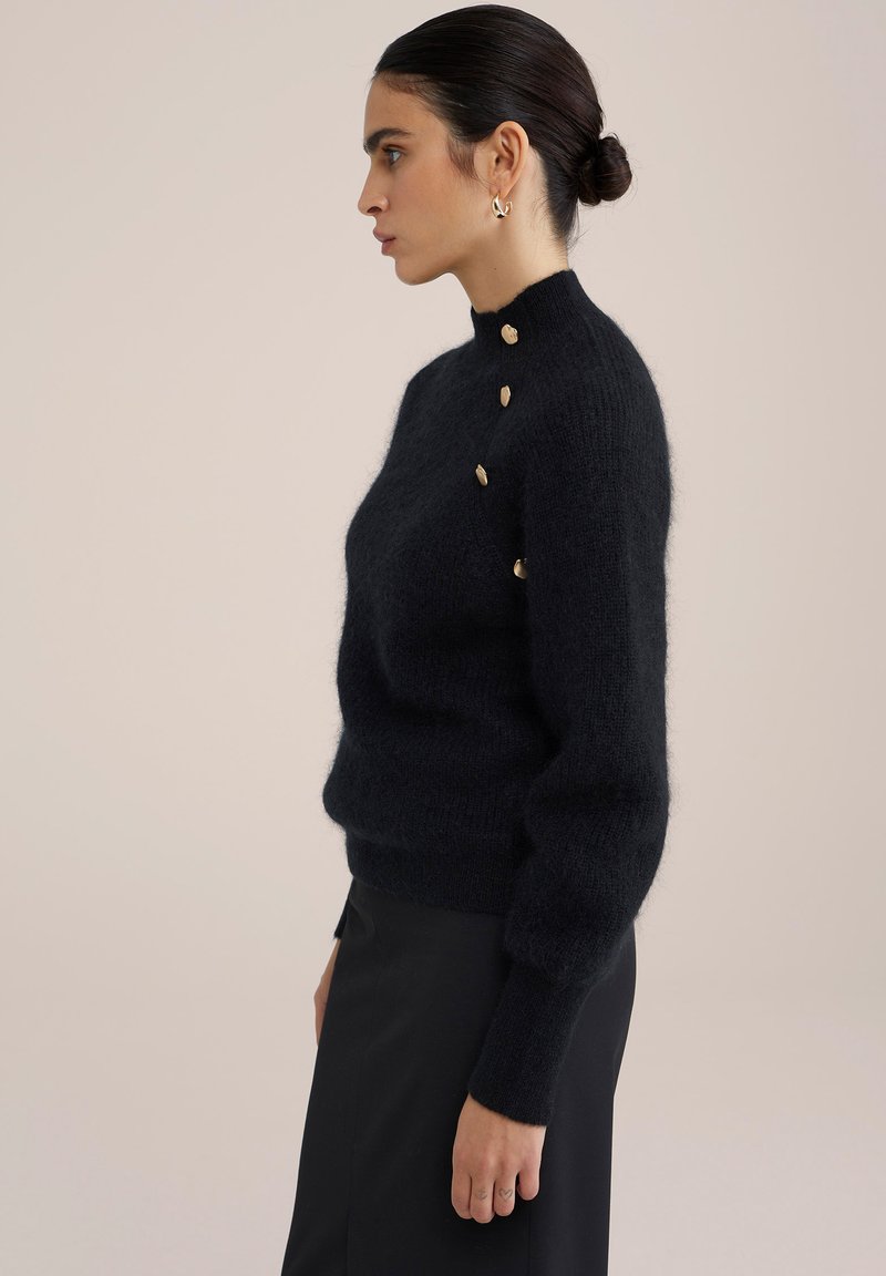 Zwarte wollen blend trui met een hoge hals, voorzien van gouden knopen op één schouder en geribde manchetten. Gladde, gestructureerde afwerking.