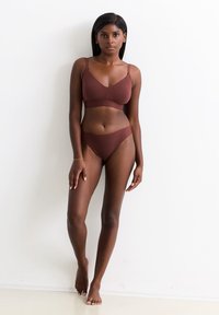 Bruine bralette en bijpassende bikini-set van zachte stof, met een eenvoudig ontwerp, verstelbare bandjes en minimale naden.