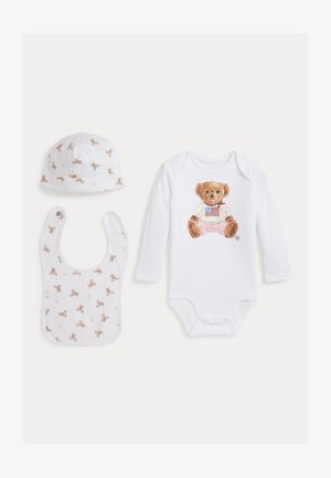 Conjunto blanco para bebé con body de manga larga con un osito de peluche con camiseta con la bandera americana, gorro a juego con estampado de osito y babero.