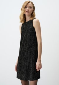 Schwarzes ärmelloses Kleid aus einem strukturierten, schimmernden Stoff, mit einem lässigen Schnitt und gerader Silhouette, das bis zur Mitte des Oberschenkels reicht.