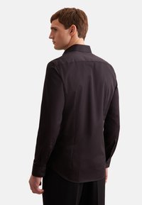 Zwarte blouse met lange mouwen, voorzien van een puntig kraag, gladde stof en knoopmanchetten, met een getailleerde pasvorm en een afgeronde zoom.