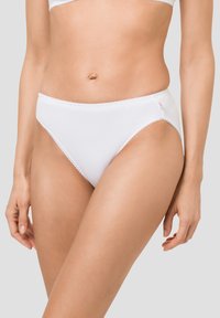 Weiße Baumwollunterwäsche mit glatter Textur, gewelltem Spitzenbesatz an der Taille und einem kleinen Logo-Akzent an der Seite. Die Kombination wird auf einem Modell präsentiert.