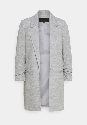 Harmaa bleiseri, jossa on teksturoitu kangas, viisto kaulus ja rypytetyt hihat. Avoin etuosa ja kaksi sivutaskua. Vuorattu vaaleanharmaalla.