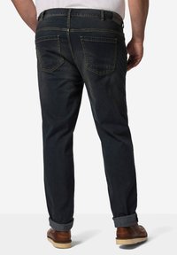 Jeans in denim blu scuro con una vestibilità comoda, dotati di tasche posteriori e orli arrotolati. Il materiale è testurizzato con leggere sfumature e cuciture a contrasto.