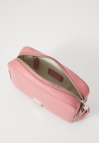 Rosa läderfodral med dragkedja som har polerad silverdetaljer, rundade kanter och en slät yta. Insidan är beige med en liten etikett.