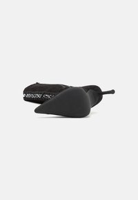 Pantofi cu toc din suede negru, cu vârf ascuțit și toc din cauciuc, având un accent texturat pe spate și închidere cu fermoar pe lateral.