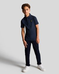 Marineblå polo med krage og tre knapper, med en liten gul logo; kombinert med marineblå bukser og hvite joggesko.
