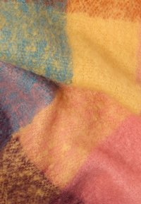 Tissu patchwork multicolore présentant des textures douces et moelleuses en jaune, rose, bleu et violet, avec des motifs variés et une apparence chaleureuse.
