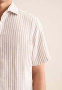 Camicia di lino a maniche corte con strisce verticali alternate in beige chiaro e bianco, dotata di colletto classico e patta con bottoni.