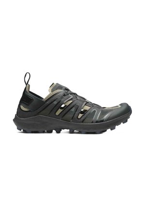Zapatillas deportivas negras con una superficie texturizada, que cuentan con correas elásticas, una puntera reforzada y una suela resistente para ofrecer tracción.