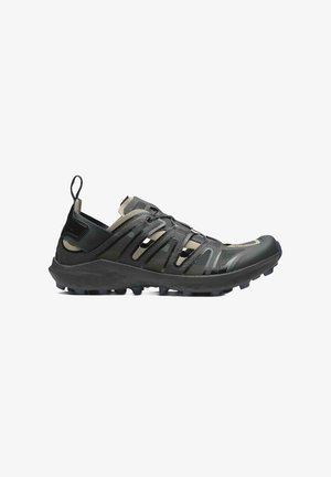Zapatillas deportivas negras con una superficie texturizada, que cuentan con correas elásticas, una puntera reforzada y una suela resistente para ofrecer tracción.