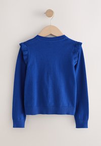 Maglione blu lavorato a maglia con una texture liscia. Presenta dettagli arricciati sulle spalle, collo e polsini a coste. Appeso a una gruccia di legno.