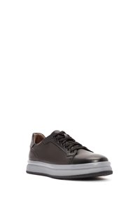 Zapatilla de cuero negro con punta redonda, cordones en la parte frontal, textura suave, suela de goma y acentos grises en la entresuela.