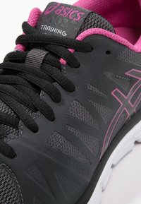 Scarpe da training nere e grigie con dettagli rosa, dotate di una tomaia testurizzata, sezioni in mesh, logo sulla linguetta e lacci neri.
