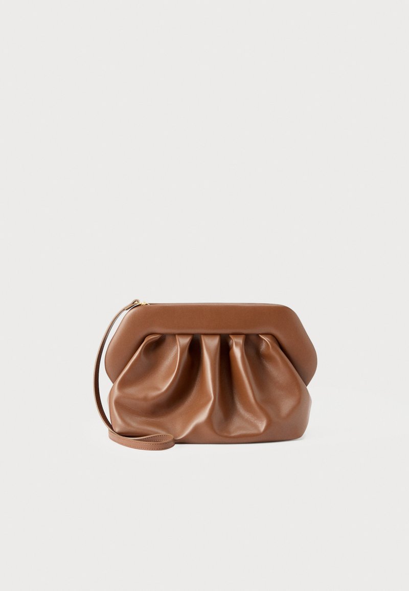 Καφέ δερμάτινο πορτοφόλι χειρός με λεπτομέρεια ρυτίδωσης, δομημένη κορνίζα, λουράκι καρπού και χρυστό φερμουάρ σε απλό ανοιχτό φόντο.