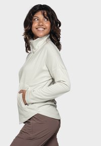 Hellbeige Zip-Up-Pullover mit hohem Kragen und langen Ärmeln; verfügt über eine Fronttasche und ein tailliertes Design. Strukturiertes Gewebe.