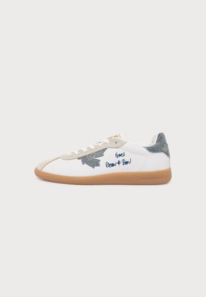 Baskets blanches avec écusson feuille d’érable en denim bleu, semelle beige, bout beige, lacets blancs et texte manuscrit bleu où il est écrit "Grazi Dean & Dan."