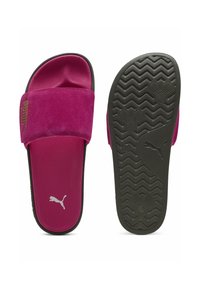 Rožiniai zomšiniai šlepetės su plačia juosta, paminkštinta padu ir tekstūruotu juodu guminiu padu, kuriame yra zigzago raštas. Rodyklė su Puma logotipu.