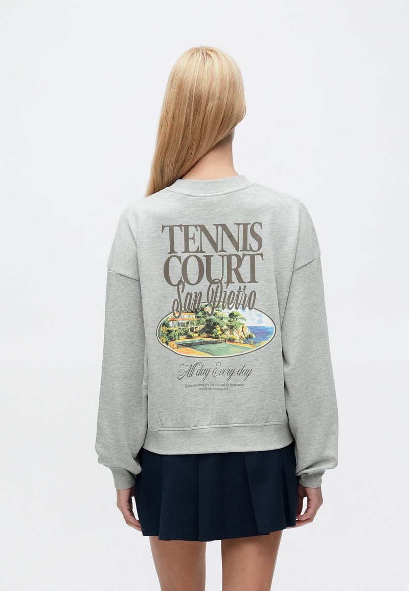 Γκρι φλις φούτερ με γραφικό πίσω μέρος που απεικονίζει γήπεδο τένις και τοπίο, με το κείμενο "TENNIS COURT San Pietro". Μακριά μανίκια, ριμπ τελείωμα.