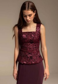 Top peplum burdeos con escote cuadrado, patrón floral texturizado y acentos brillantes. La tela suave se extiende hacia un diseño ajustado por debajo de la cintura.
