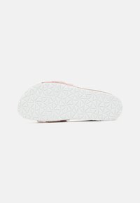 Schuhe mit einer strukturierten weißen Gummisohle und einem weichen pinken Obermaterial aus Wildleder oder ähnlichem Material. Geschlossenes Design mit minimaler Detailierung.