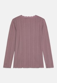 Halenka s dlhým rukávom v svetlomauve farbe so ribbovanou textúrou a čipkovým lemom na výstrihu. Mäkka tkanina so zúženým lemom na rukávoch a dolnom okraji.