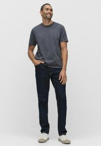Mørkeblå jeans med lige ben, parret med en grå t-shirt med korte ærmer og rund hals. Sneakers i neutrale toner fuldender outfittet.