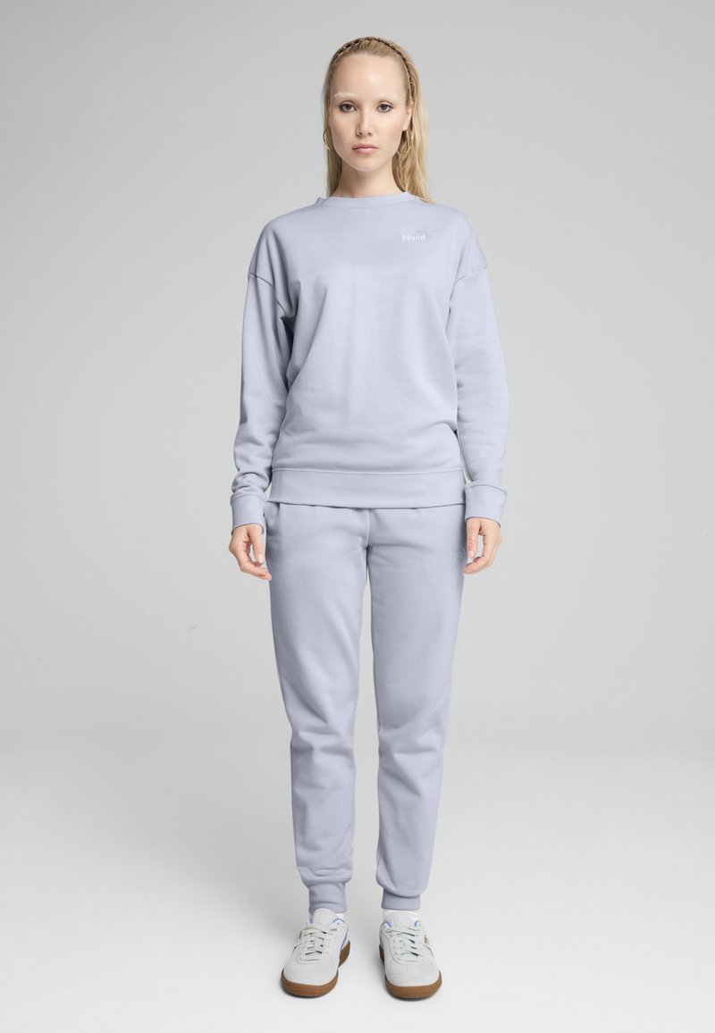 Felpa grigia chiara e pantaloni jogger realizzati in tessuto morbido. La felpa ha un collo a giro e polsini a costine; i pantaloni jogger sono dotati di vita elastica e polsini.