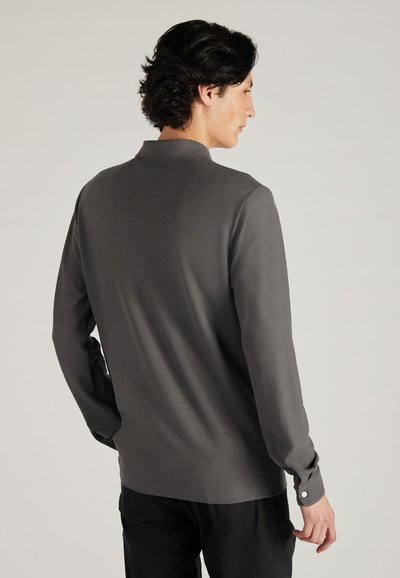 Długa koszula z długim rękawem w ciemnoszarym kolorze, wykonana z miękkiego materiału. Posiada kołnierz, zapięcia na guziki na mankietach oraz gładką, matową fakturę. Minimalistyczny wzór bez zdobień.