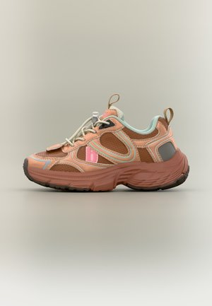 Ένα μοναδικό καφέ και ροδακινί αθλητικό παπούτσι με λεπτομέρειες σε μέντα, παχιά σόλα και ραβδώσεις έλξης στη φτέρνα και στη γλώσσα σε απλό φόντο.